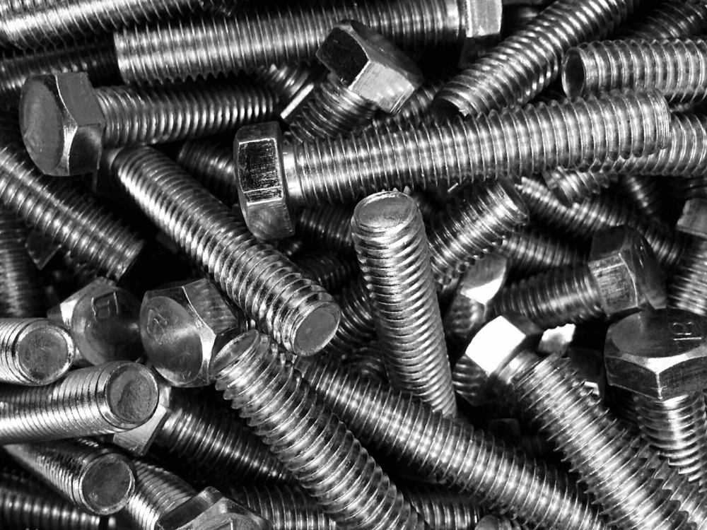 Diversos parafusos sextavados metálicos agrupados, evidenciando modelos com rosca métrica usados em equipamentos e estruturas.